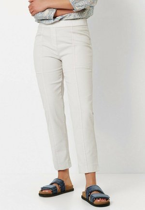 Light beige pants with a straight cut and seam detailing, paired with blue sandals featuring adjustable straps and a flat sole.