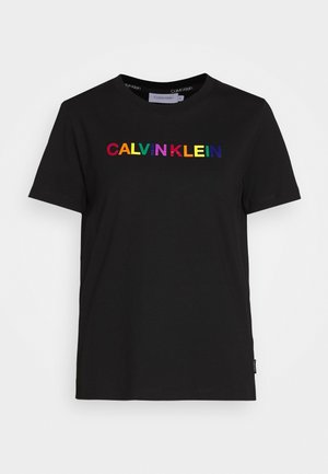 Czarny bawełniany t-shirt z okrągłym dekoltem ozdobiony napisem „CALVIN KLEIN” w kolorach tęczy na wysokości klatki piersiowej. Krótkie rękawy i standardowy krój.