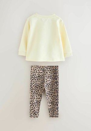 Svetlo rumen dolg rokav z okrolim izrezom, kombiniran s črnimi in rjavimi legicami z leopardjim vzorcem. Mehka tkanina, sproščen kroj za udobje.