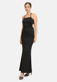 Schwarzes, ärmelloses Maxikleid mit tailliertem Oberteil, seitlichen Ausschnitten und verzierten Akzenten. Glatter Stoff mit ausgestellt gesäumtem Saum. Hochhackige Sandalen sind im Lieferumfang enthalten.