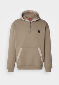 Khaki bluza z kapturem z półzamkiem, pikowane jasnobeżowe akcenty na kapturze i kieszeni, ściągacze na mankietach oraz mała czarna naszywka z logo.