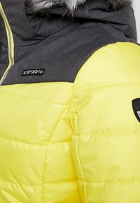 Fodrad vinterjacka med en ljusgul kropp och mörkgrå axlar. Har en huva med fuskpälsfoder och kontrasterande tygtexturer.