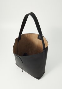 Borsa tote in pelle nera con interno in suede, caratterizzata da un design minimalista, due manici lunghi e una chiusura superiore con un laccio in pelle.
