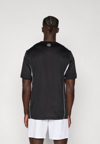 Maillot de sport noir à manches courtes, avec des rayures blanches sur les côtés et un col rond. Fabriqué en tissu respirant.