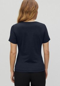 T-paita, lyhythihainen, tummansininen, pyöräkuosisella kaula-aukolla, sileä pinta ja vartalonmyötäinen muotoilu, näkyy takaa.