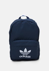 Marinblå ryggsäck i tyg med en framficka, ett handtag på toppen och en vit adidas-logotyp i form av ett blad.