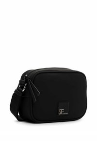 Czarna prostokątna torba z gładkiego materiału. Zamek błyskawiczny z dwoma suwakami. Na przodzie znajduje się naszywka z logo, a także regulowany pasek.