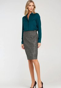 Turkusowa bluzka z guzikiem z przodu, zestawiona z teksturowaną szarym ołówkową spódnicą, uzupełniona ciemnoczerwonymi szpilkami. Dopasowany krój, długie rękawy.