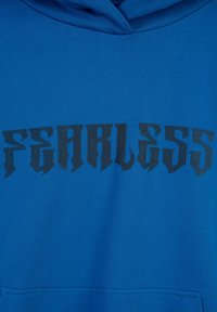 Niebieska bluza z kapturem z czarnym stylizowanym tekstem w pionowe paski "FEARLESS" na klatce piersiowej oraz widoczną na dole kieszenią.