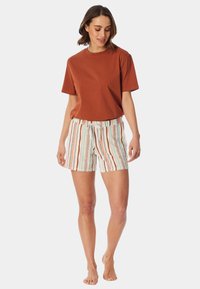 Hnědý bavlněný tričko v kombinaci s pruhovanými šortkami v bílé, světle zelené, oranžové a hnědé barvě. Šortky mají stahovací pas a boční kapsy.