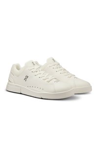 Scarpe sportive bianche con tomaia in pelle liscia, chiusura con lacci e dettagli perforati sui lati. Presentano suola ammortizzata per il comfort.