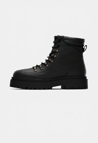 Fekete bőrből készült bokacsizma kerek orral, kontrasztos ezüst hardware-rel, fűzős dizájnnal, párnázott gallérral és strapabíró talppal a tapadás érdekében.