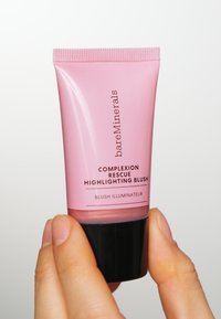 Rosa tub av Bare Minerals Complexion Rescue Highlighting Blush med en svart bas. Har en slät textur och en minimalistisk design.