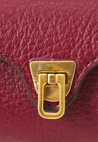 Burgundy leather handbag with a textured surface, featuring a gold-tone clasp and contrasting black edge stitching.