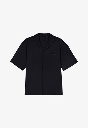 Must musta, lühikeste varrukatega nööbitav särk, mis on valmistatud ribakanga. Omab kaelust ja sõna "PECADOR" trükitud valge värviga vasakule küljele.