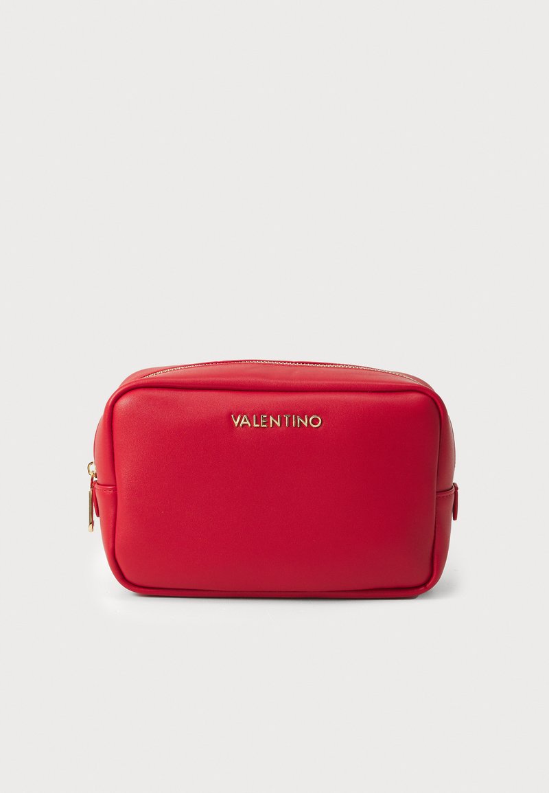 Red, smooth faux-leather rectangular bag with gold logo and zipper. Features a side pocket and minimal stitching for a sleek design.
