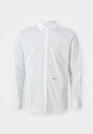 Camisa blanca de manga larga con botones que presenta un cuello clásico, corte recto y un pequeño logotipo negro en la parte inferior delantera. Textura de algodón suave.