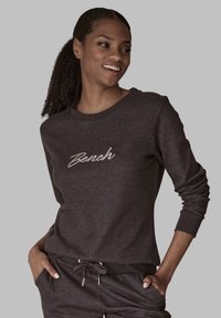 Dunkelgrauer Pullover mit Rundhalsausschnitt und langen Ärmeln. Mit weißem, gesticktem "Bench"-Logo auf der Vorderseite. Weicher Stoff und lockere Passform.