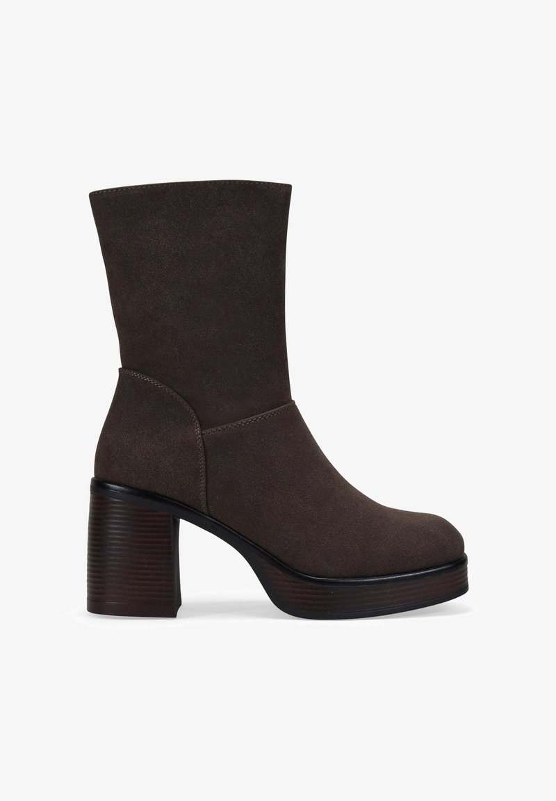 Botín de ante marrón oscuro con puntera redondeada, tacón de bloque apilado y caña a media pantorrilla, mostrado en perfil lateral.