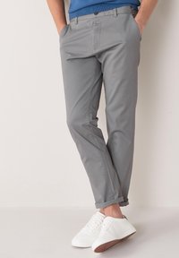 Gray chinos with a slim fit, featuring a flat front and side pockets, paired with white sneakers. Smooth fabric and clean design.