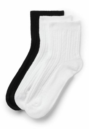 Deux paires de chaussettes côtelées mi-mollet, une noire et une blanche, posées à plat et se chevauchant sur un fond blanc.