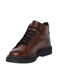 Stivale alla caviglia in pelle marrone con lacci neri, occhielli metallici, punta arrotondata e suola in gomma nera texturizzata.