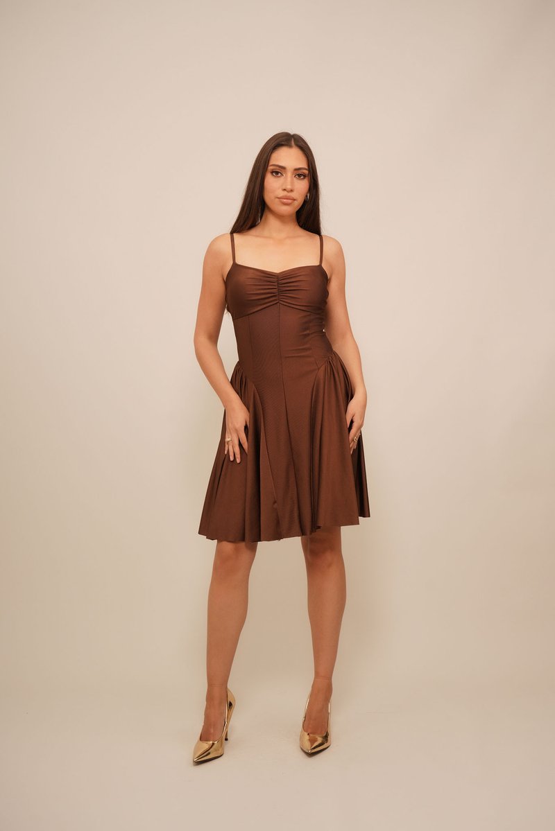 Braunes, ärmelloses Kleid mit tailliertem Oberteil, gerafftem Detail am Ausschnitt und einem ausgestellten Rock. Getragen mit goldenen High Heels.