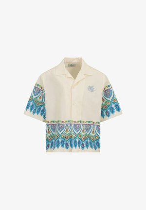 Camisa crema de manga corta con patrones florales y de plumas en azul, verde y rojo en las mangas y el dobladillo inferior, con un pequeño logo de pájaro en el pecho.