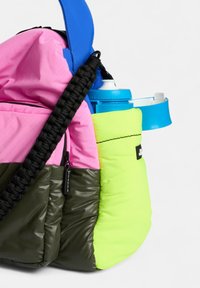 Mehrfarbige Tasche aus pinken, grünen und schwarzen Materialien; verfügt über einen blauen Tragegurt und eine Tasche für eine Wasserflasche. Gepolsterte Oberfläche.