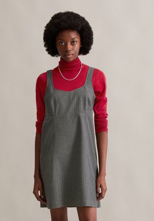 Gray pinstriped dress with a square neckline, layered over a fitted red turtleneck. Textured fabric with a relaxed fit. Silver chain necklace accent.