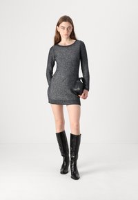 Sparkly black long-sleeve mini dress with a scoop neckline, paired with black knee-high crocodile-embossed leather boots and a small handbag.