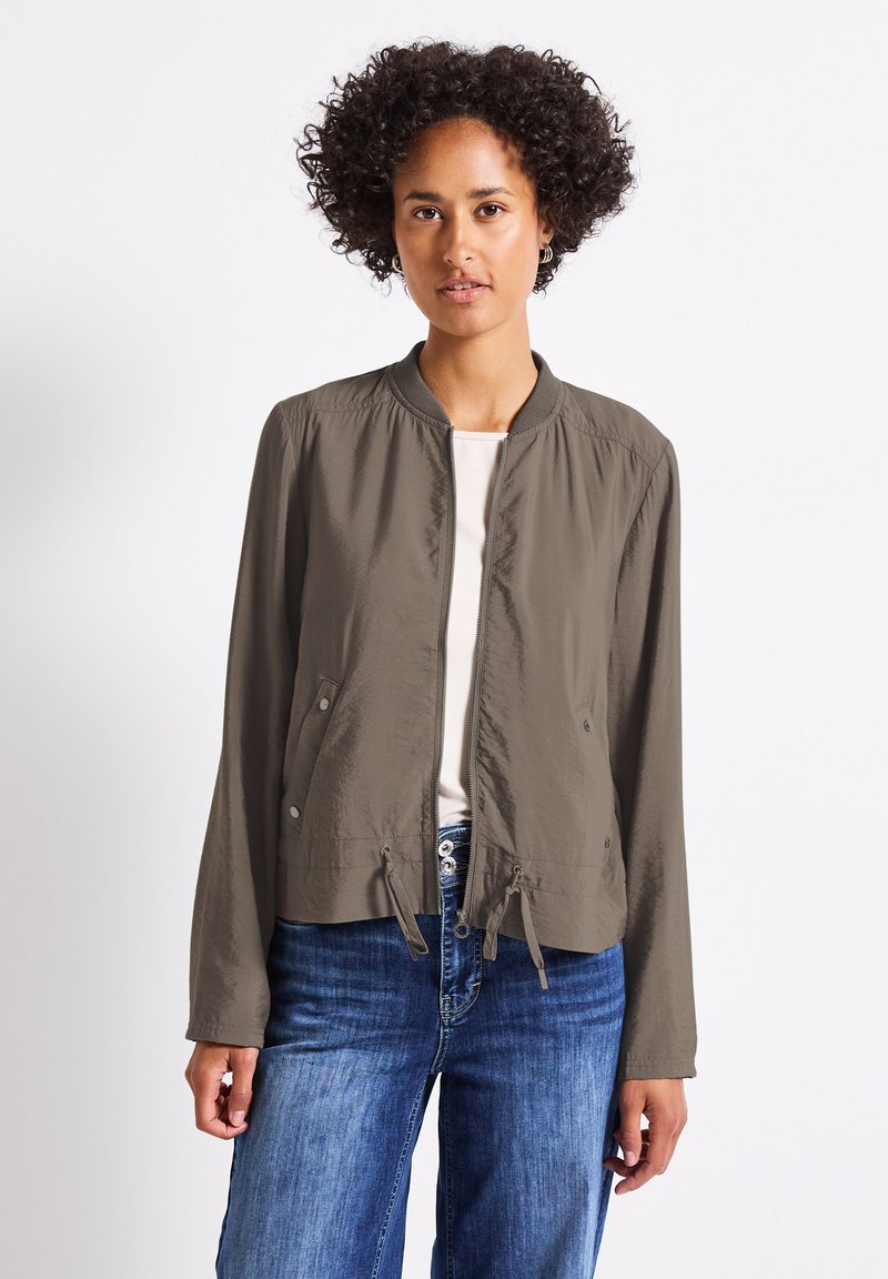 Olivově zelená bomber bunda s předním zipem, elastickými manžetami a stahovací spodní částí. Hladká tkanina, dvě boční kapsy a jednoduchý design.