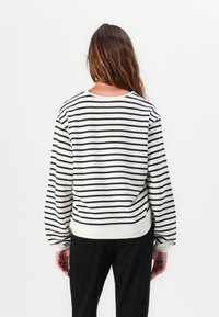 Stripet sweatshirt i myk stoff, med svarte og hvite horisontale striper, rund hals, og ribbestrikkede mansjetter og kant. Bakside vist.