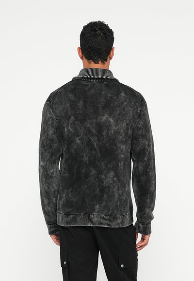 Veste en velours côtelé noir avec une finition texturée, dotée d'un col et de poignets côtelés. La vue de dos montre une coupe décontractée et un motif unique.