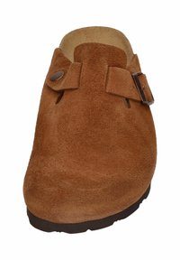 Sabots en daim marron à enfiler avec une pointe arrondie, dotés d'une sangle en cuir réglable et d'une boucle en métal. Tige texturée et semelle en caoutchouc.