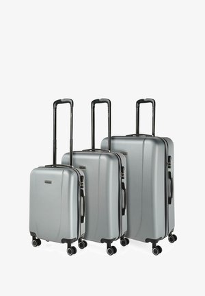 Tres maletas rígidas plateadas en tamaños pequeño, mediano y grande, con asas telescópicas negras extendidas y cuatro ruedas negras cada una.