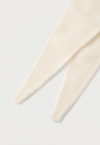 Pletená, krémovo biela šatka s jemným, textúrovaným povrchom. Má predĺžené, špicaté konce a útulný vzhľad.