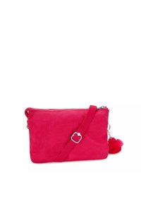 Borsa a tracolla rossa in tessuto con chiusura zip, tracolla regolabile e un soffice pom-pom decorativo attaccato alla cerniera. Texture liscia.