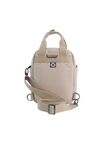 Beige fabric bag with two top handles, adjustable shoulder strap, and a small side pocket. Features a black logo patch on front.