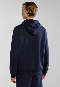 Sudadera azul marino hecha de mezcla de algodón, con capucha ajustable, puños acanalados y un corte relajado, detalles de costura visibles en las costuras.