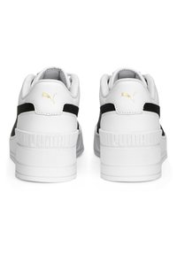 Białe sneakersy z czarnymi akcentami, teksturowana gumowa podeszwa, wytłoczone logo "PUMA" na pięcie oraz złoty detal logo z tyłu.