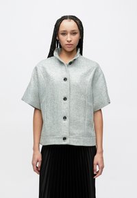 Kortærmet jakke med krave i et lysegråt fiskebenmønster, med sorte knapper og en lige nederste kant.