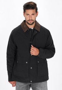 Sort jakke med en brun corduroy krave, frontknapper med tryk, og to store lommer. Glat tekstur, afslappet design, mellemlang pasform.