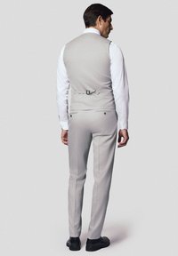 Jasnoszary garnitur z kamizelką i dopasowanymi spodniami, charakteryzujący się gładką fakturą i dopasowanym krojem. Czarne buty dopełniają całość.