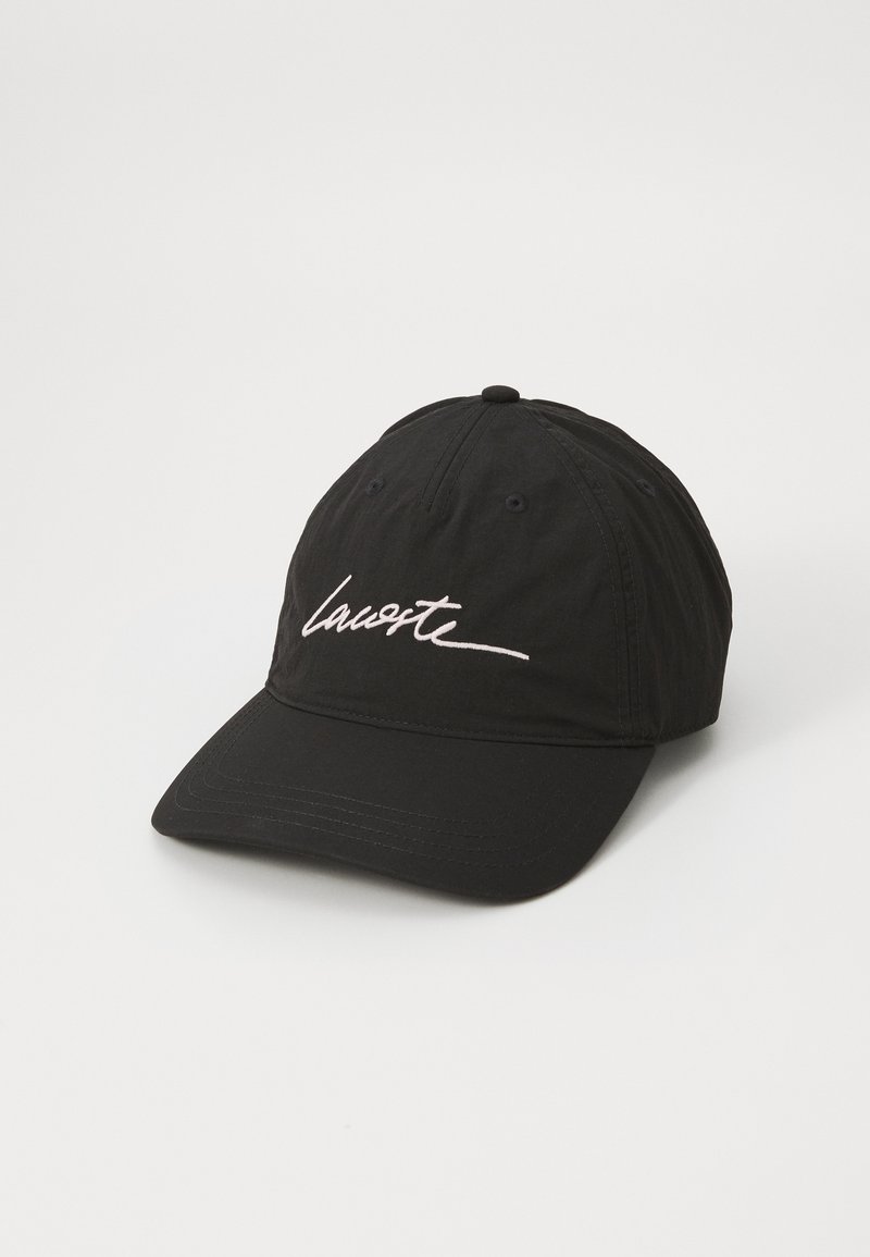 Fekete vászon baseballsapka ívelt billentével. Elöl fehér hímzett "Lacoste" logó található. Hátul állítható pánt.