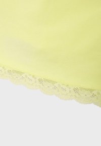 Tissu jaune clair avec un bord en dentelle festonné présentant des motifs floraux le long du bord inférieur.