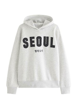 Jasnoszara bluza z kapturem z czarnymi, w kropki napisanymi literami tworzącymi słowo „SEOUL” i mniejszym koreańskim tekstem poniżej.