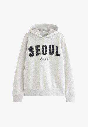 Lysegrå hættetrøje med sorte prikprikkede bogstaver, der staver "SEOUL" og mindre koreansk tekst nedenunder.