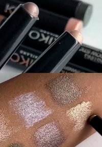 Gli stick trucco KIKO in confezione nera mostrano campionature sulla pelle: tonalità argentate shimmer, bronzo, oro e taupe con finiture riflettenti.