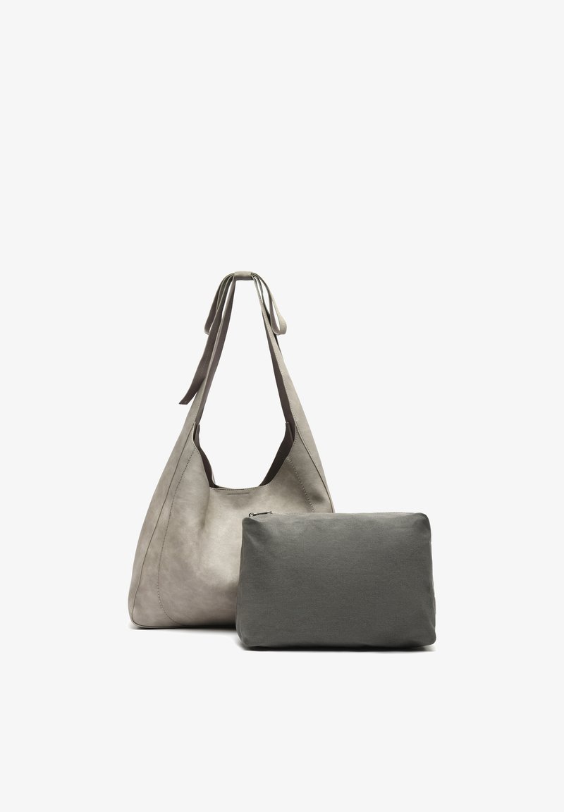 Pilka odinė petnešėlė su plačiomis rankenomis šalia mažesnio tamsiai pilkos spalvos stačiakampio su užtrauktuku dėklo ant balto fono.